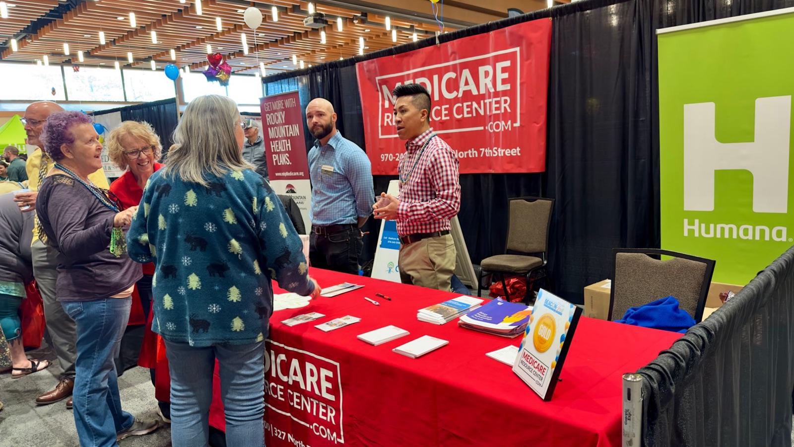 Medicare Resource Center agents talking with visitors at a community event booth