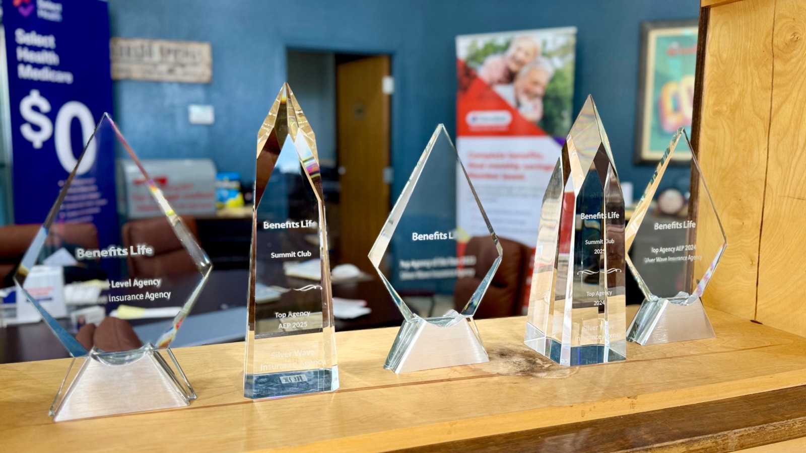 Benefits Life Top Agency and Summit Club awards on a shelf in the Colorado Springs office